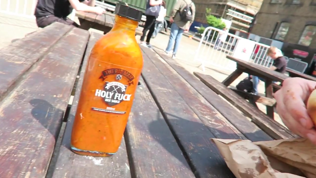 A bottle of Rib Man hot sauce on a wooden outdoor table