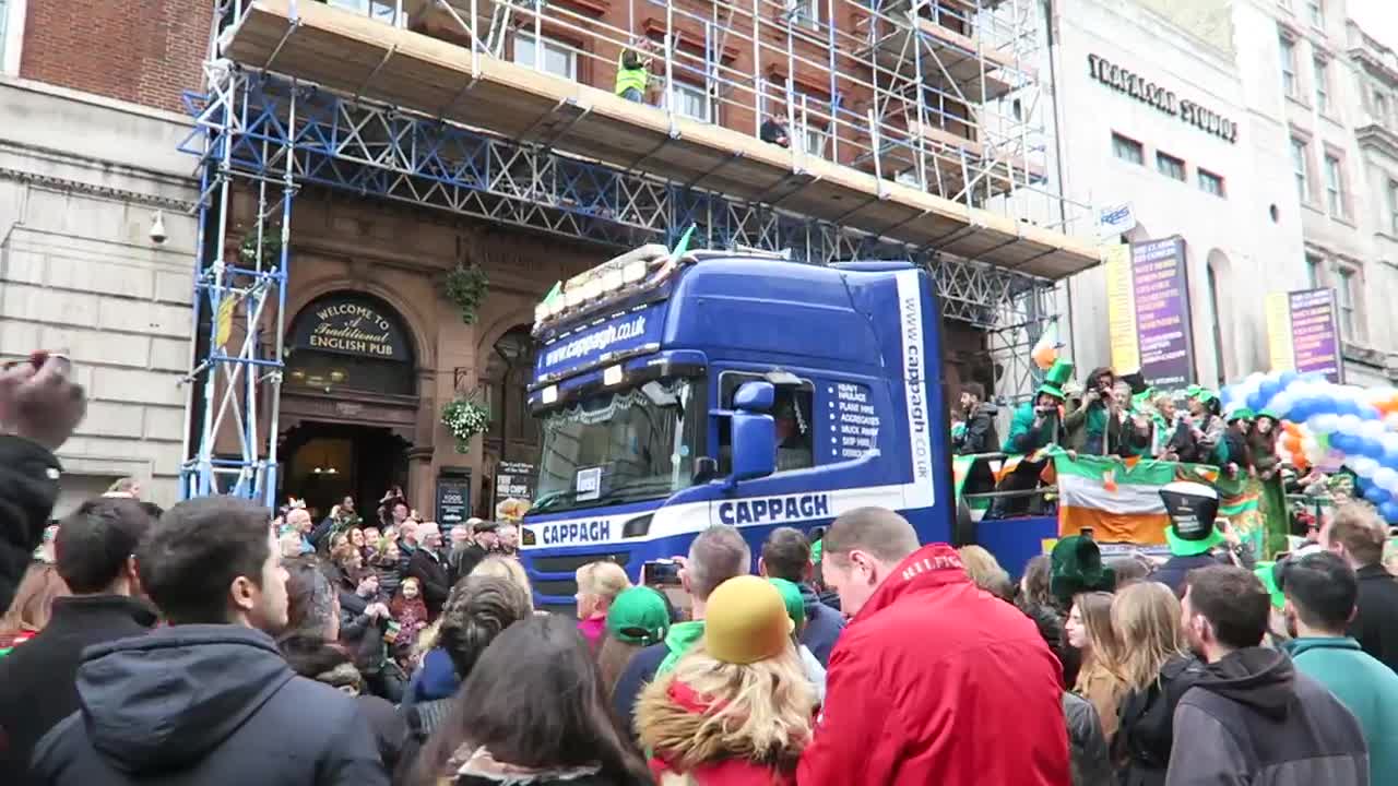 Blue parade vehicle passing spectators on a London street