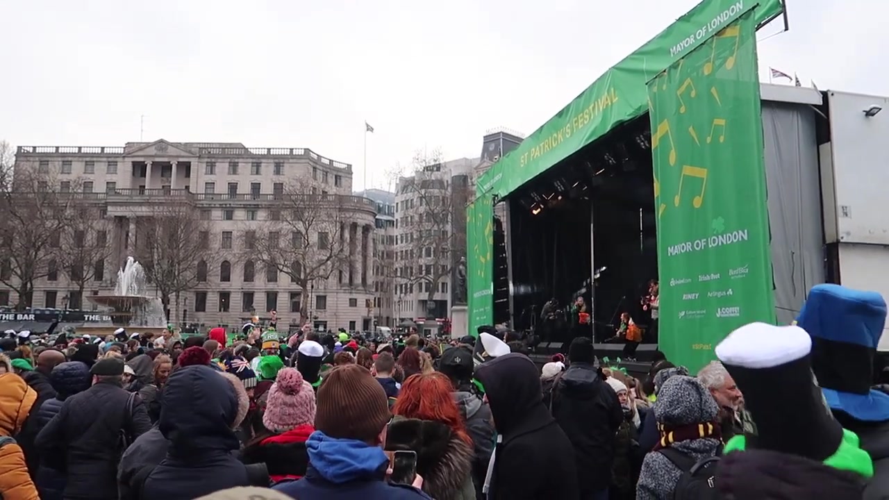 Festivalgoers watching the green-framed stage in Trafalgar Square.