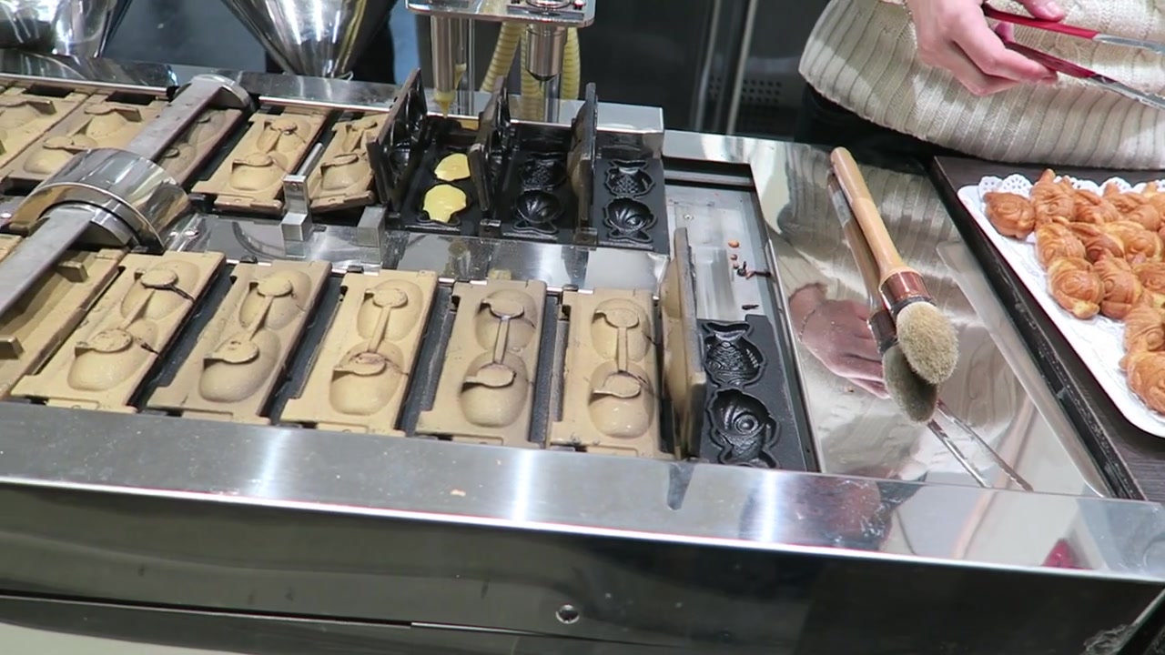 Rows of fish-shaped moulds in a taiyaki cake-making machine in Chinatown