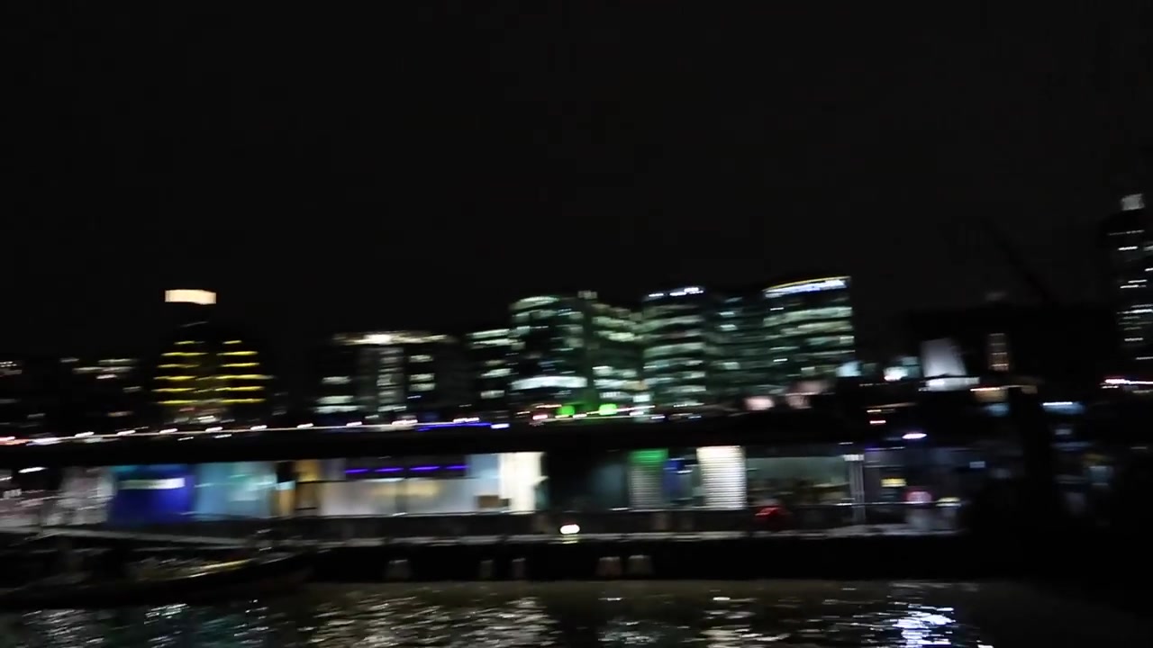 Illuminated riverside buildings seen from beside the Thames at night