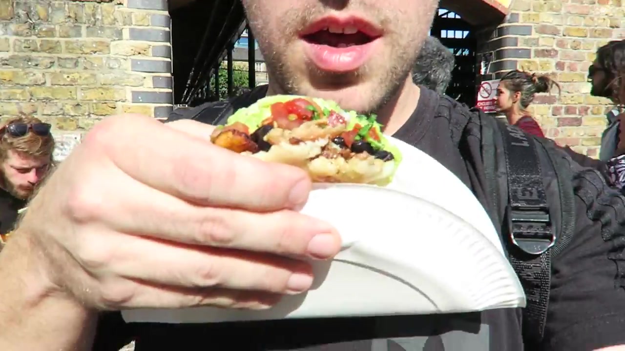 Barry holding an arepa filled with meat, salad and guacamole at Camden Market