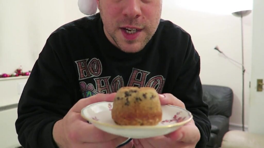 Barry holds a spotted dick pudding on a saucer during Vlogmas 2015.