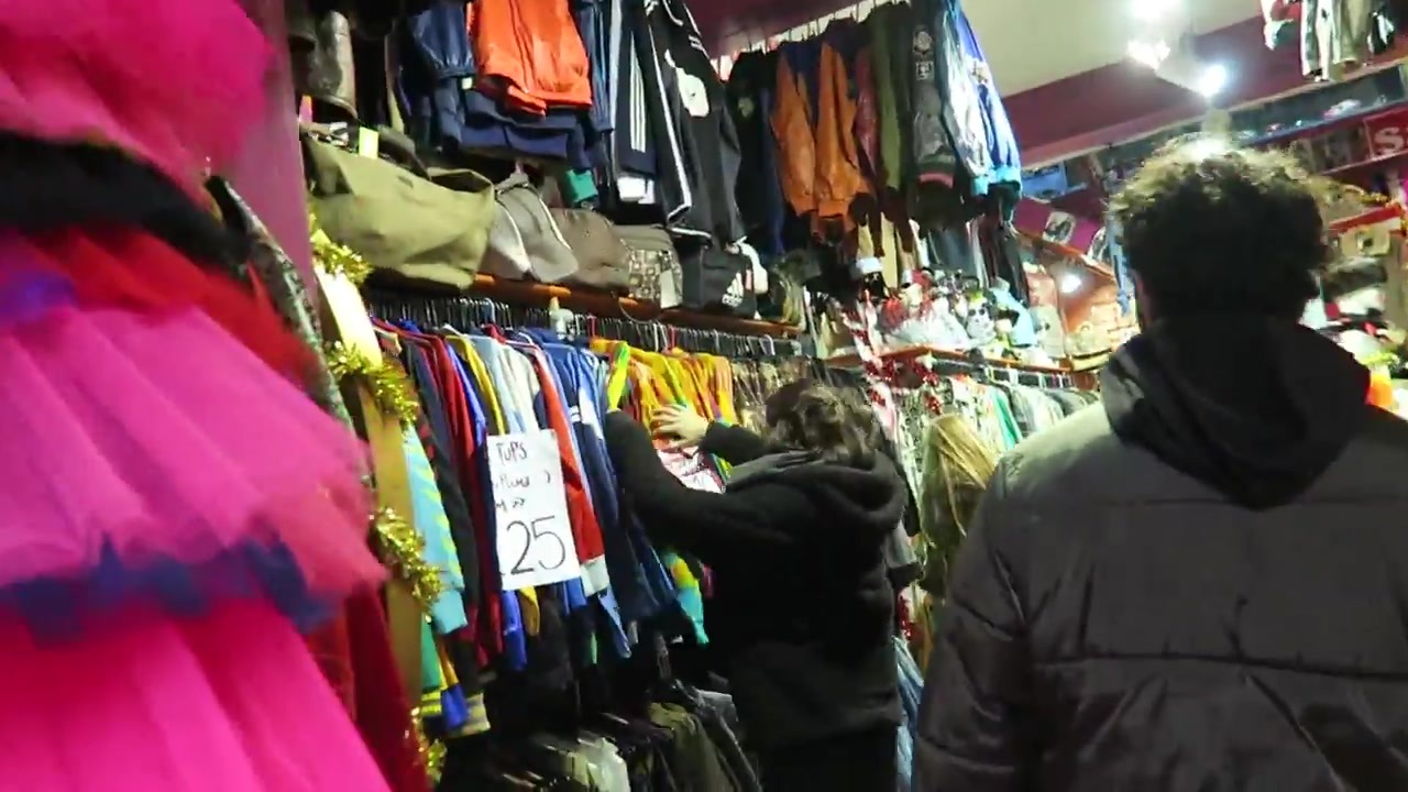 Brightly coloured clothes displayed along a narrow Camden market passage.