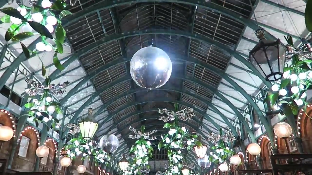 Illuminated mistletoe chandeliers and a large silver bauble inside Covent Garden Market.