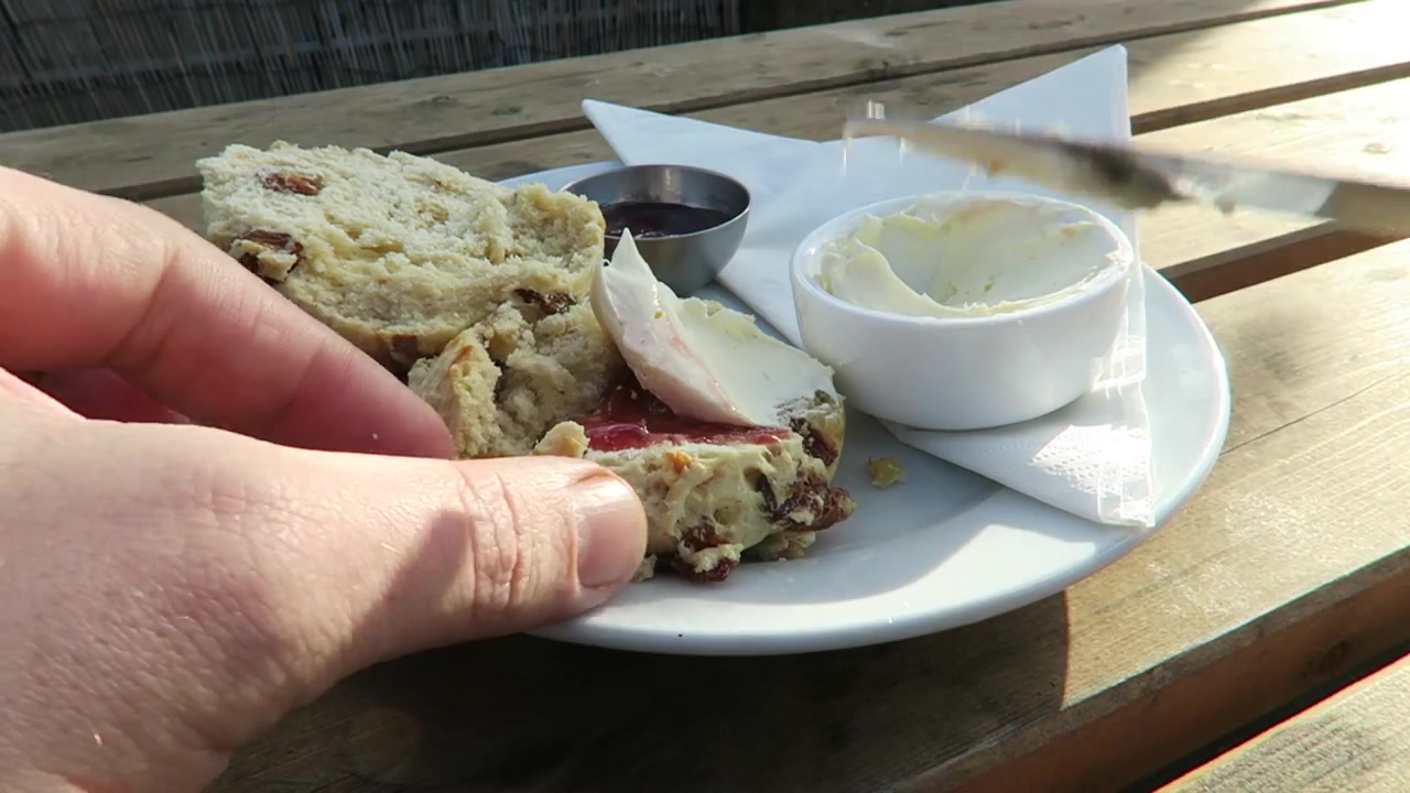 Spreading cream over strawberry jam on a scone at Alfies rooftop café
