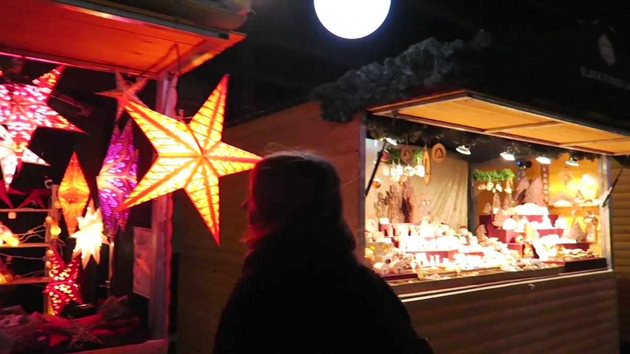 Glowing star lanterns hanging in a wooden Christmas market stall.