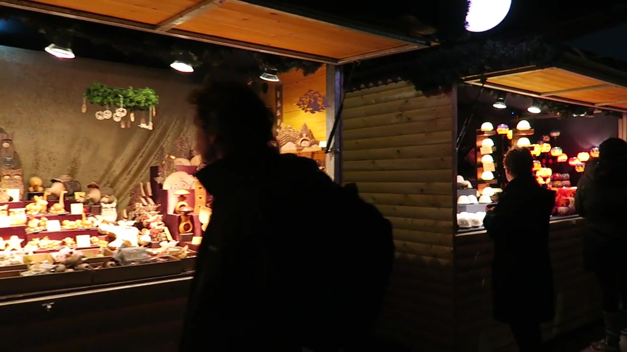 Visitors browsing illuminated wooden stalls at the Southbank Christmas market.