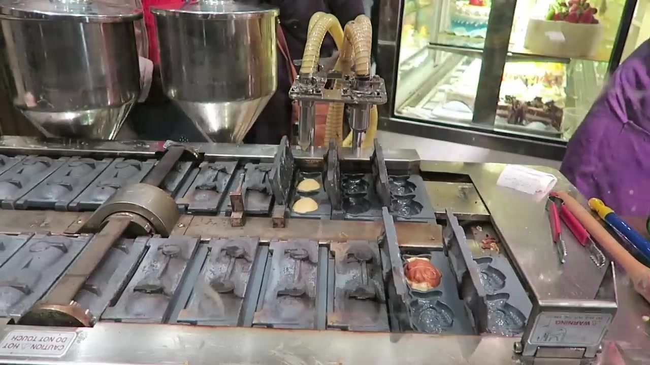 Machine with fish-shaped moulds making small cream cakes
