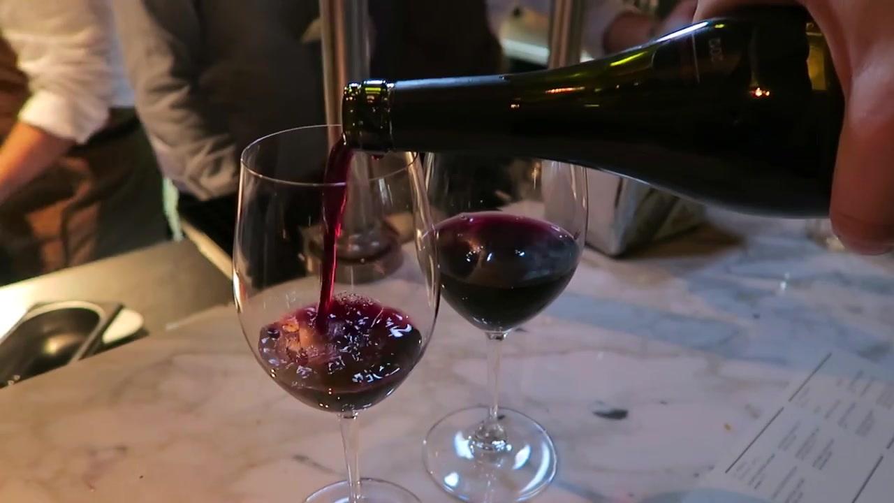 Red wine being poured into a glass at the restaurant counter