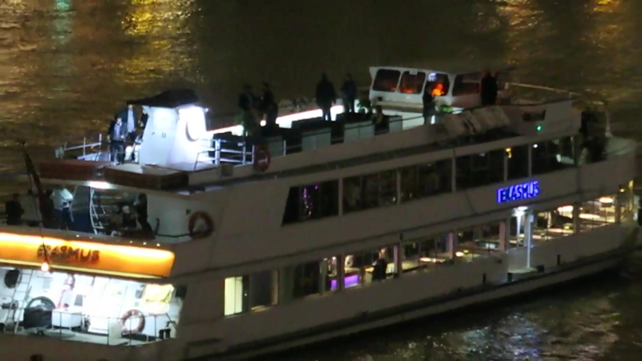 An illuminated passenger boat on the River Thames at night.