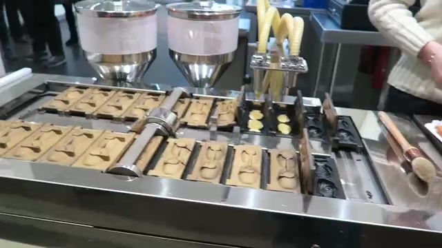 Open fish-shaped moulds and batter dispensers on a taiyaki-making machine in Chinatown.
