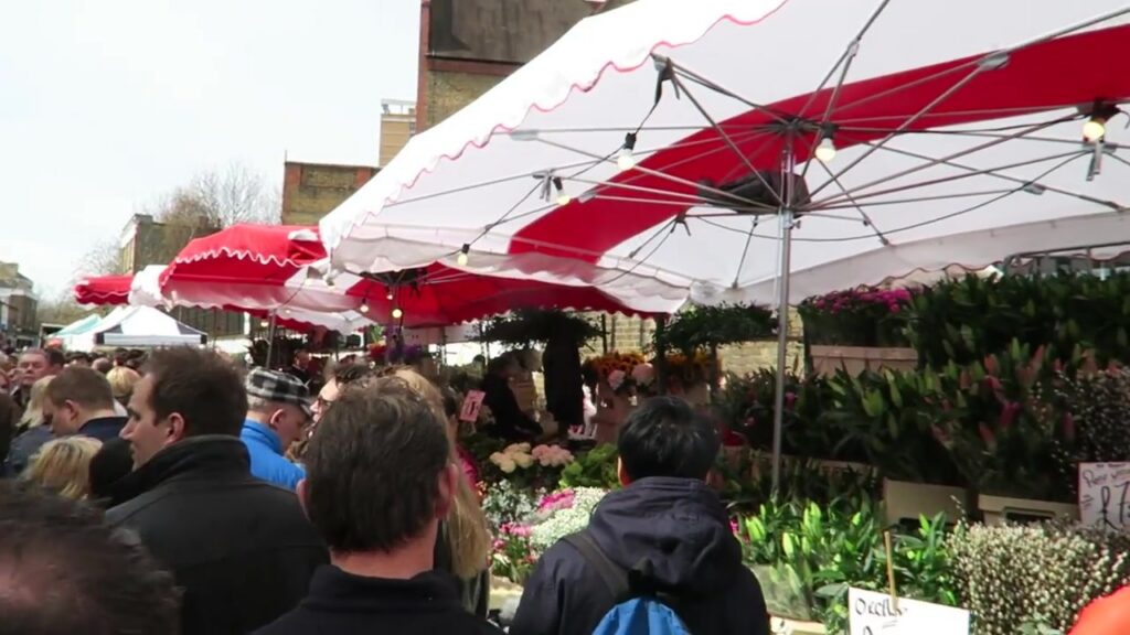 Crowds and flower stalls under red and white awnings at Columbia Road