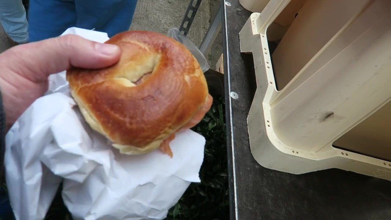 A smoked salmon and cream cheese bagel held in its paper wrapping