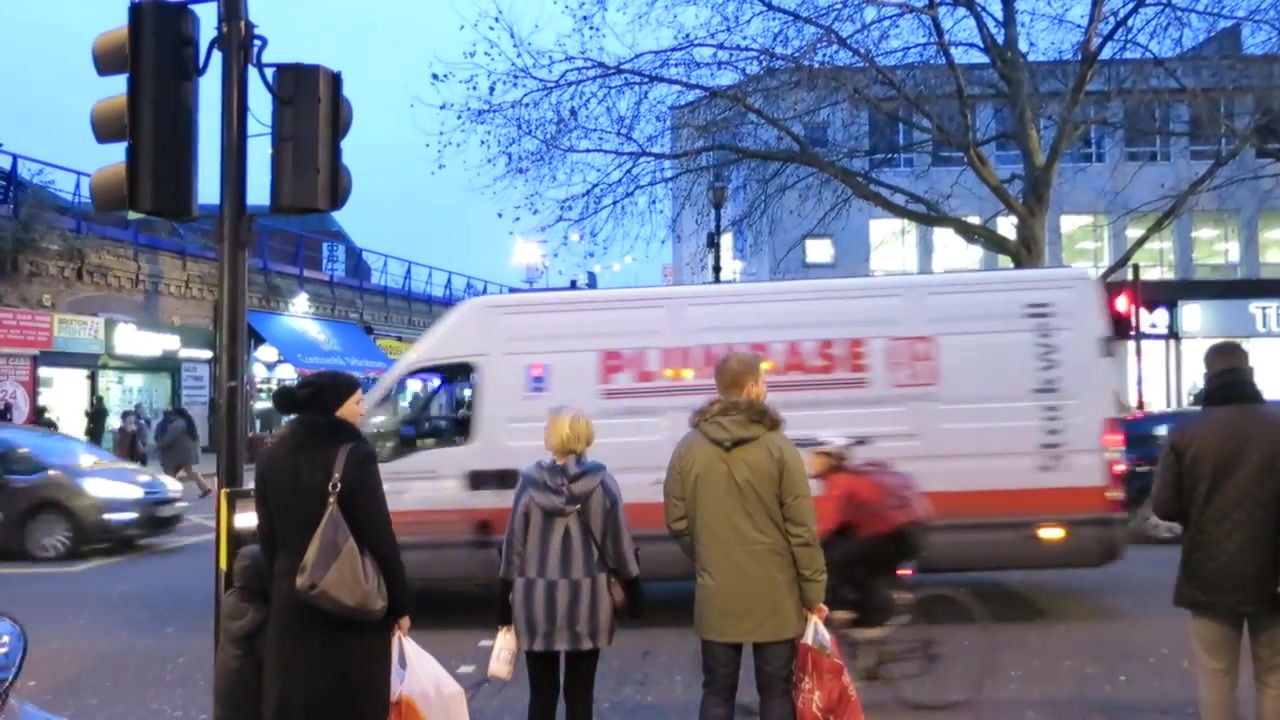 Pedestrians and traffic on a Brixton street at dusk