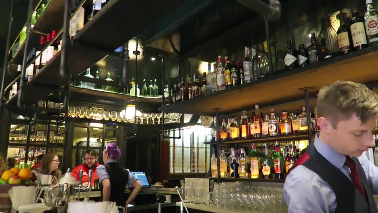 Staff working behind the bottle-lined bar at Jackson & Rye Soho during breakfast.