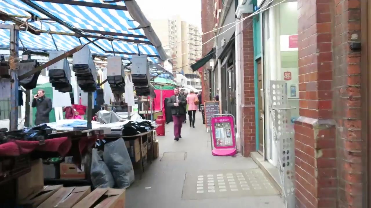 Clothing displayed under striped awnings at Leather Lane Market