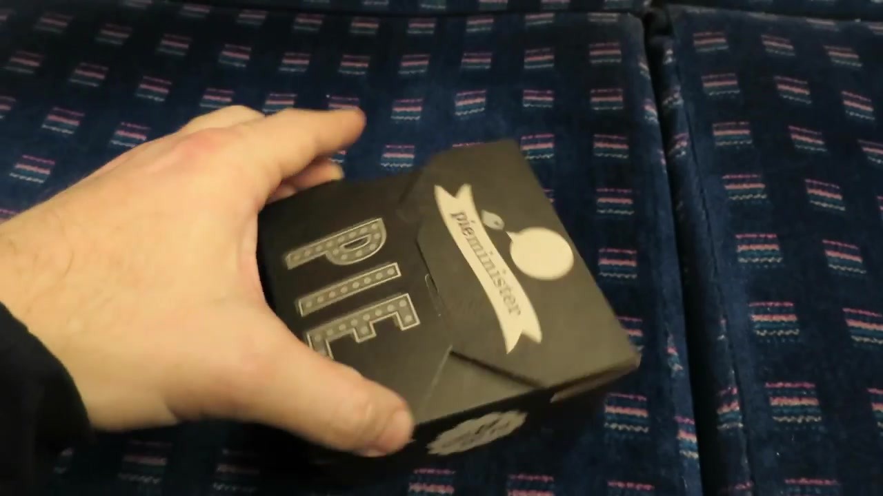 Hand holding a black Pieminister takeaway pie box