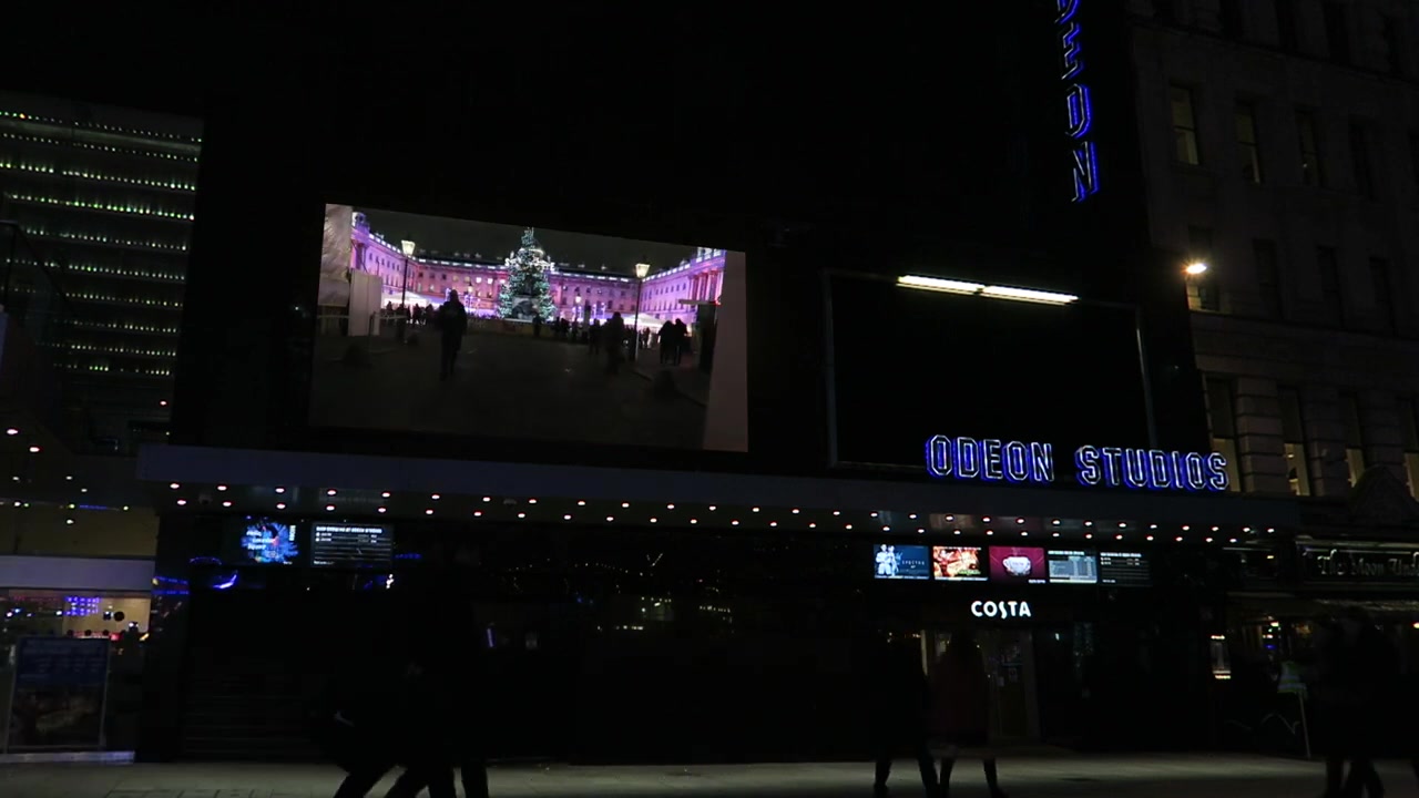 A Christmas tree and illuminated London buildings shown within the edited cinema screen montage.