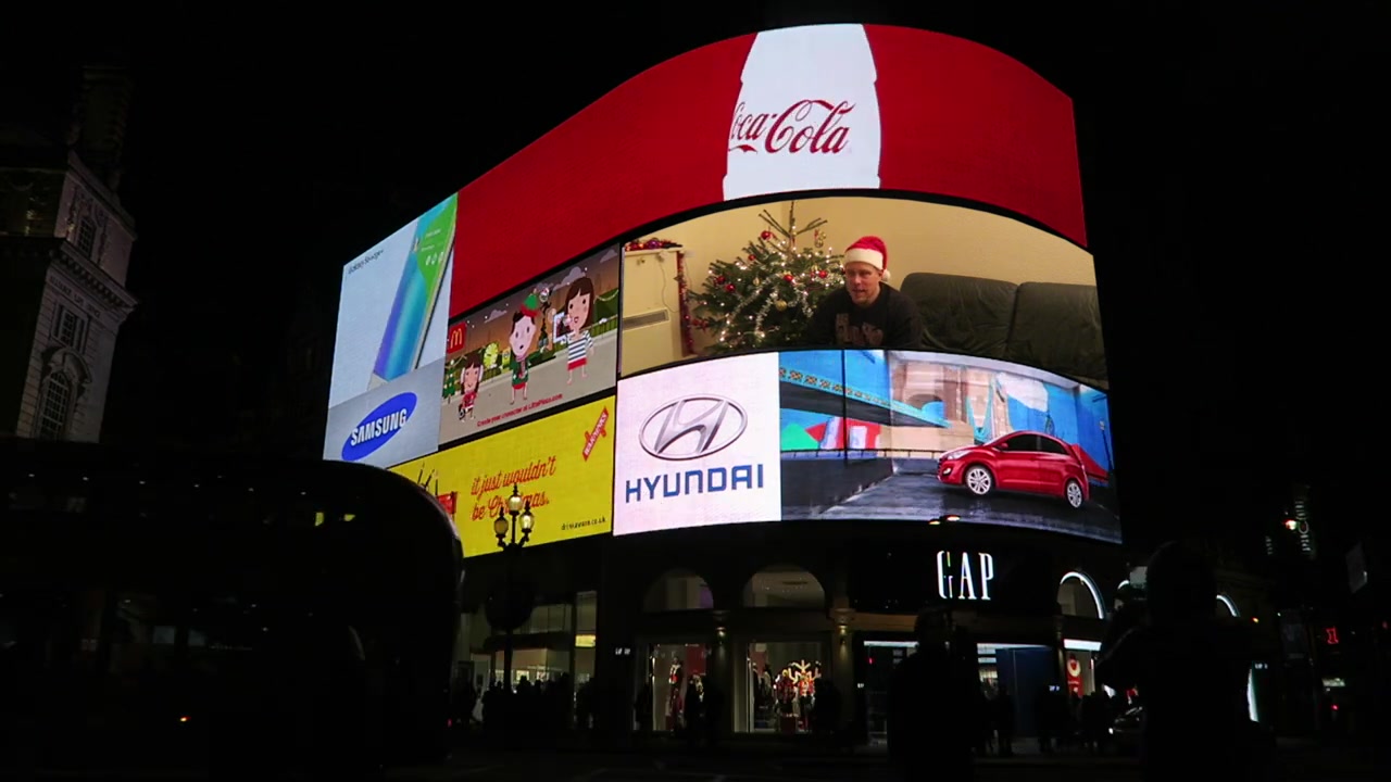 Robert in a Santa hat composited into a Piccadilly Circus billboard for the Vlogmas montage.