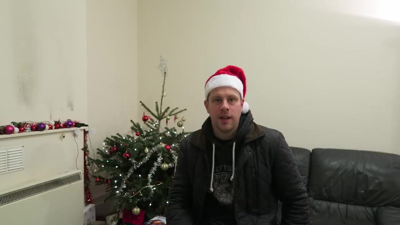 Robert in a Santa hat giving his 2015 Christmas message beside the tree.