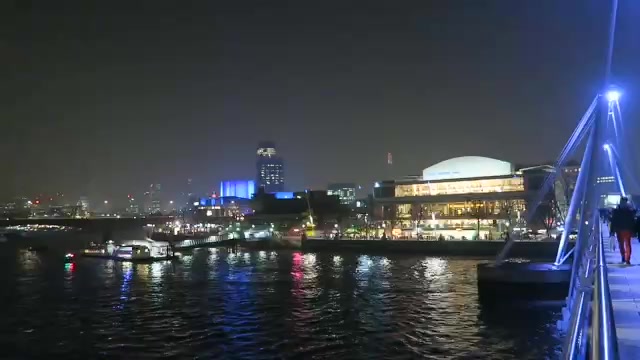 The illuminated South Bank and river seen from the bridge at night.